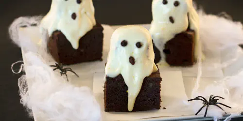 Cómo hacer simpáticos y deliciosos brownies fantasmas de Halloween. Interior de brownie clásico de chocolate y la sabana de glaseado de queso y naranja.