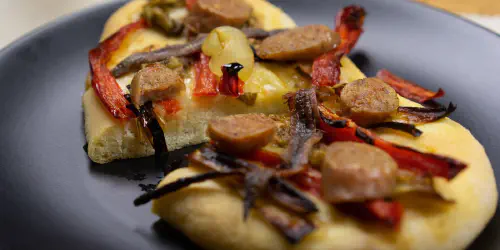 Cómo hacer una coca recapte. Una coca tradicional catalana con anchoas, escalivada y butifarra. Una forma deliciosa, fácil y con una masa casera crujiente que hará que repitas esta receta en casa.